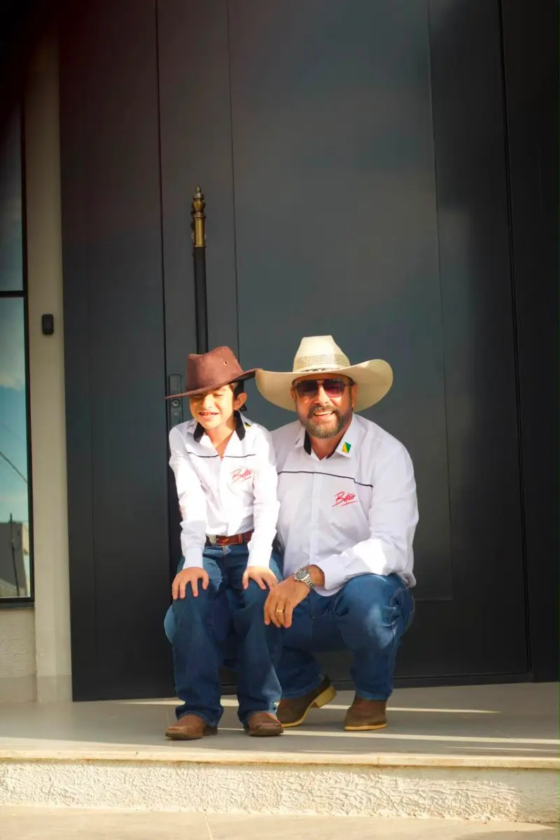 Júnior Betão agachado ao lado do filho, os dois de chapéu